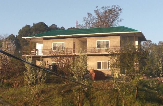 It is surrounded by lush green mountains, with fruit garden & vegetable fields.